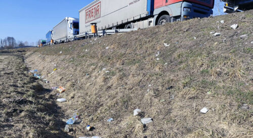 Zaśmiecone pobocze drogi krajowej z widocznymi odpadami wyrzuconymi przez kierowców, apel GDDKiA do kierowców