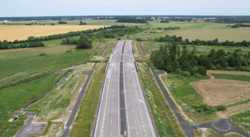 Dwujezdniowy odcinek autostrady z wiaduktem i terenami rolnymi