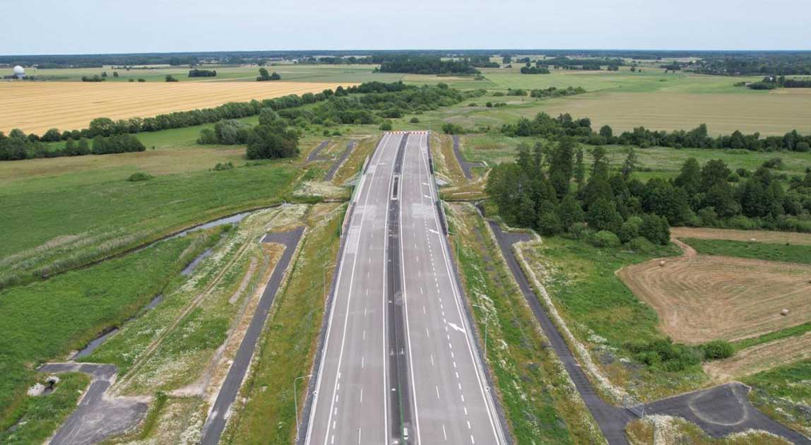Dwujezdniowy odcinek autostrady z wiaduktem i terenami rolnymi