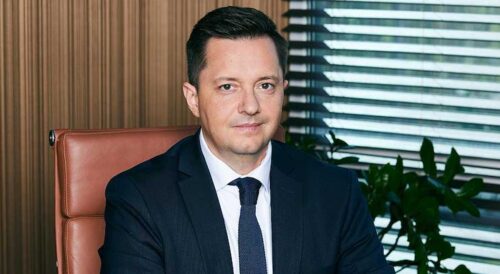 Mężczyzna w garniturze siedzący w gabinecie.