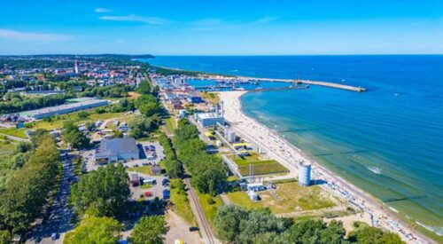 Widok z lotu ptaka na nadmorską miejscowość, plażę i port. Zdjęcie ilustracyjne.