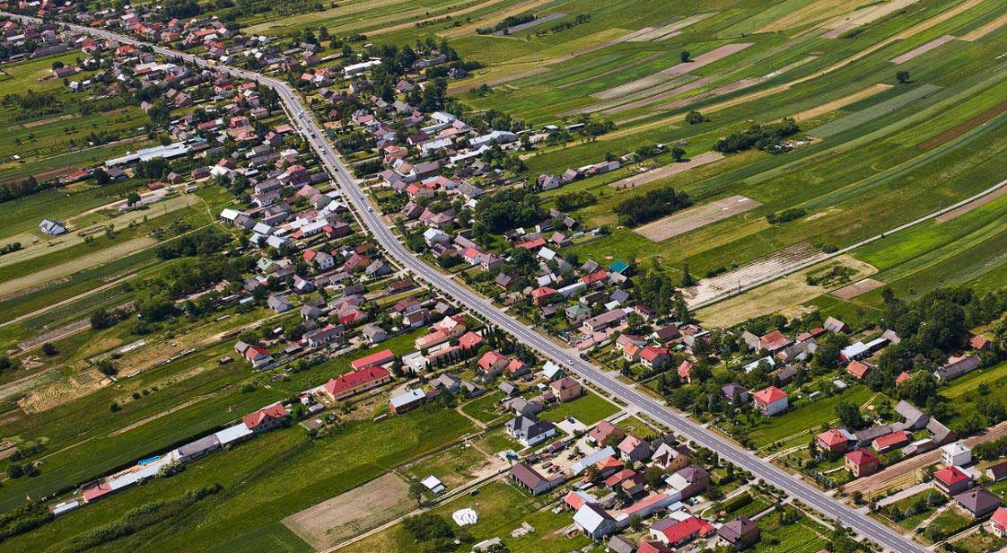 Widok z lotu ptaka na drogę krajową DK84 przebiegającą przez miejscowość przewidzianą do rozbudowy.