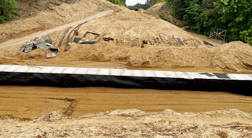 Ogólny widok warstw zasypki gruntowej w trakcie ich zagęszczania ciężkimi zagęszczarkami płytowymi