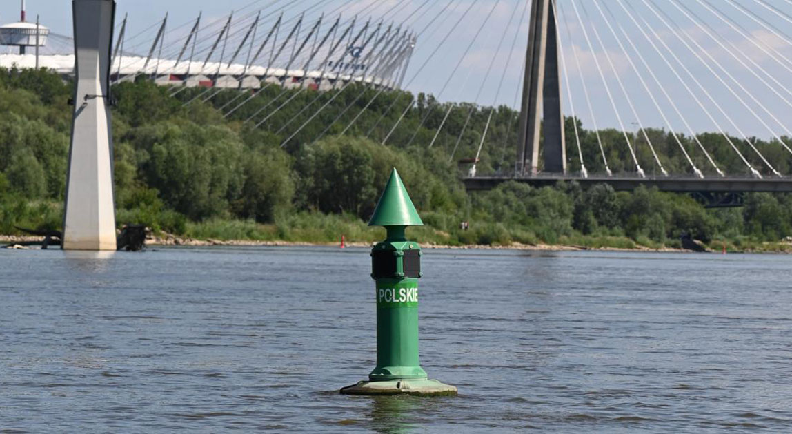 Zielony znak nawigacyjny na śródlądowej drodze wodnej z mostem w tle