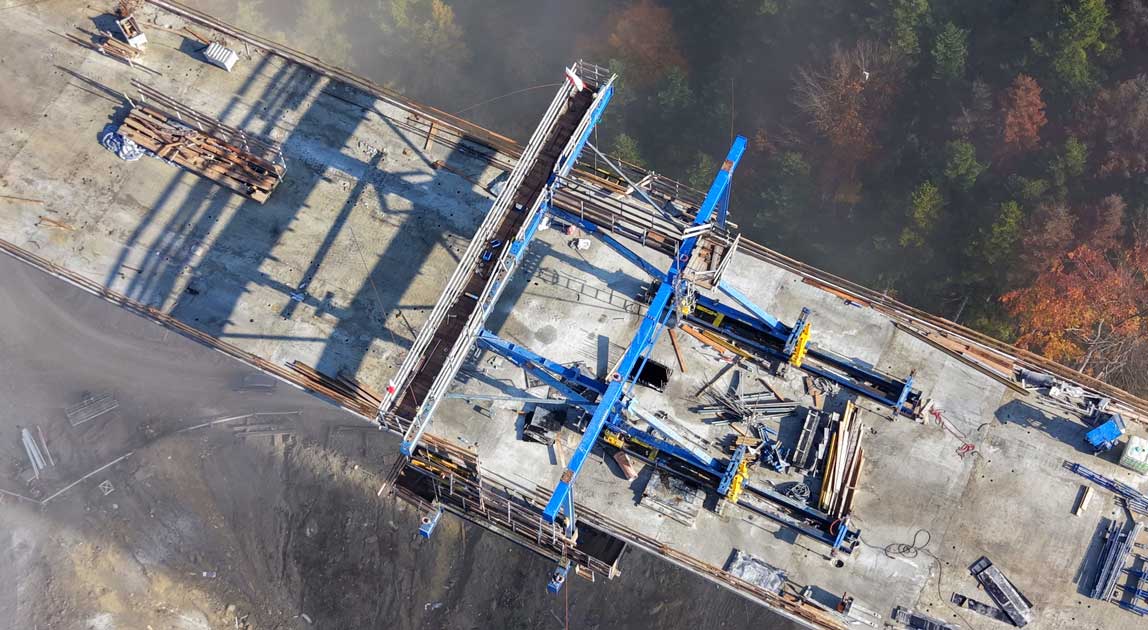 Budowa ustroju nośnego estakady ES-26 na wysokich żelbetowych filarach ponad zalesioną doliną